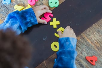 Math manipulatives - student playing with plastic numbers 